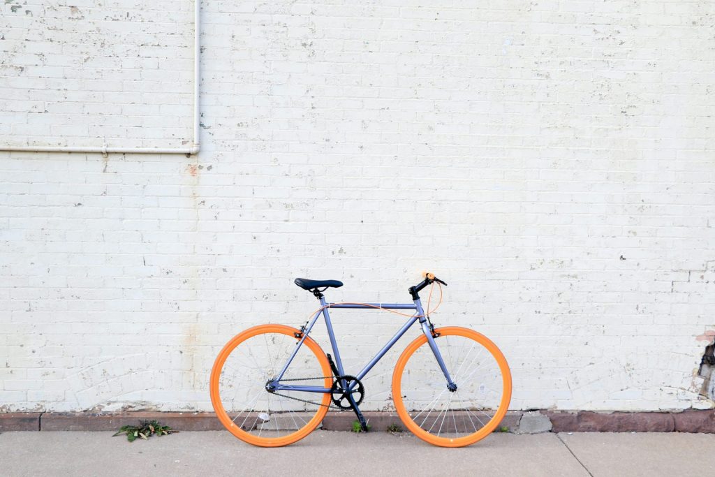 yellow and purple bicycle near white wall at daytime